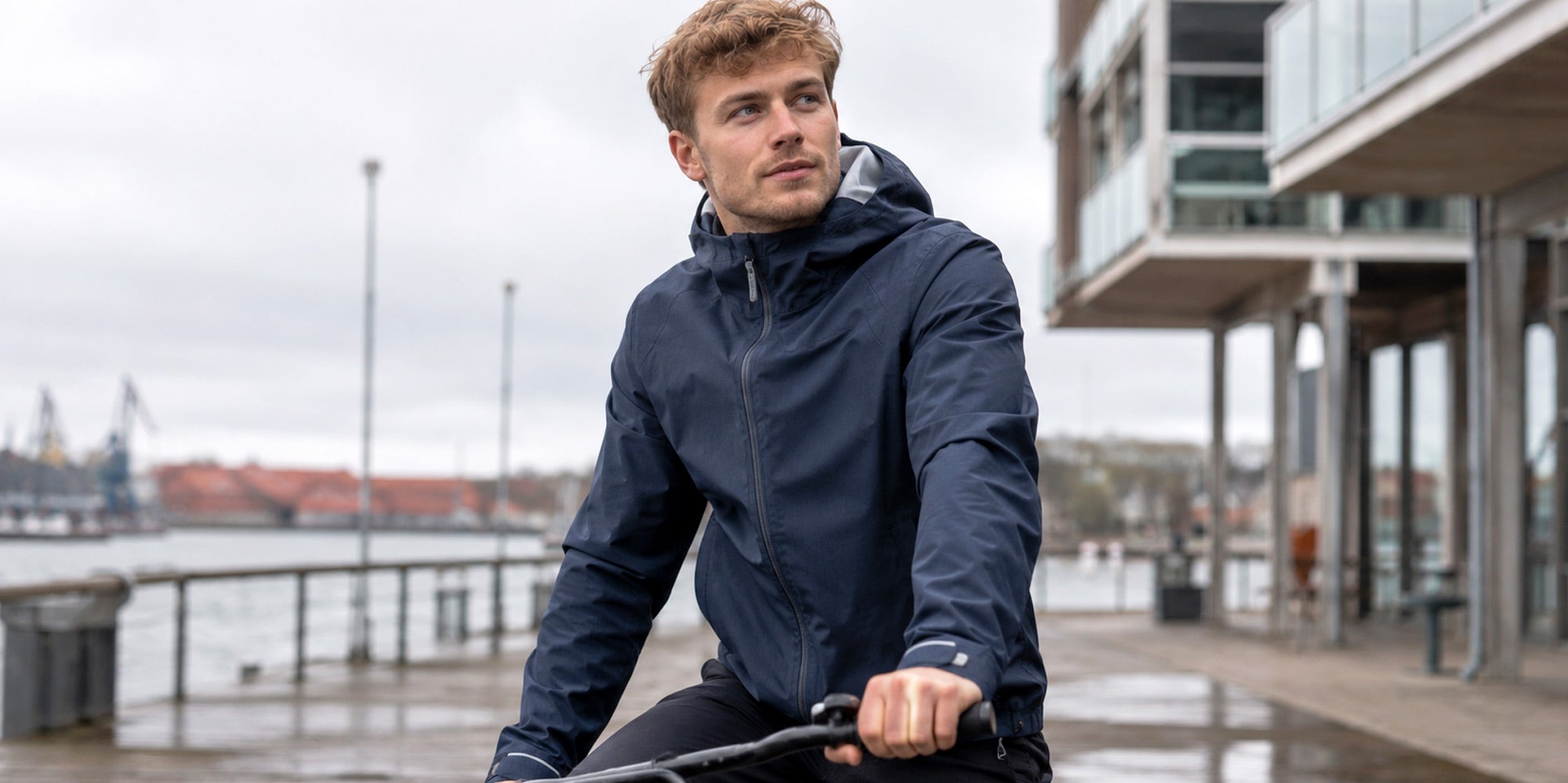 Mann mit Regenjacke "KNÜLLE" auf einem Fahrrad in der Hafencity
